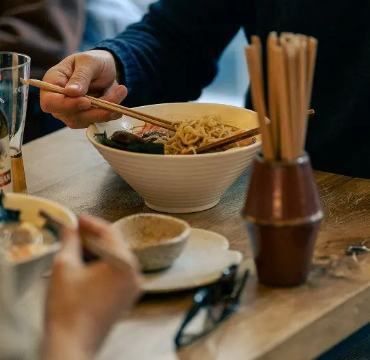 Un client care mănâncă ramen cu bețișoarele