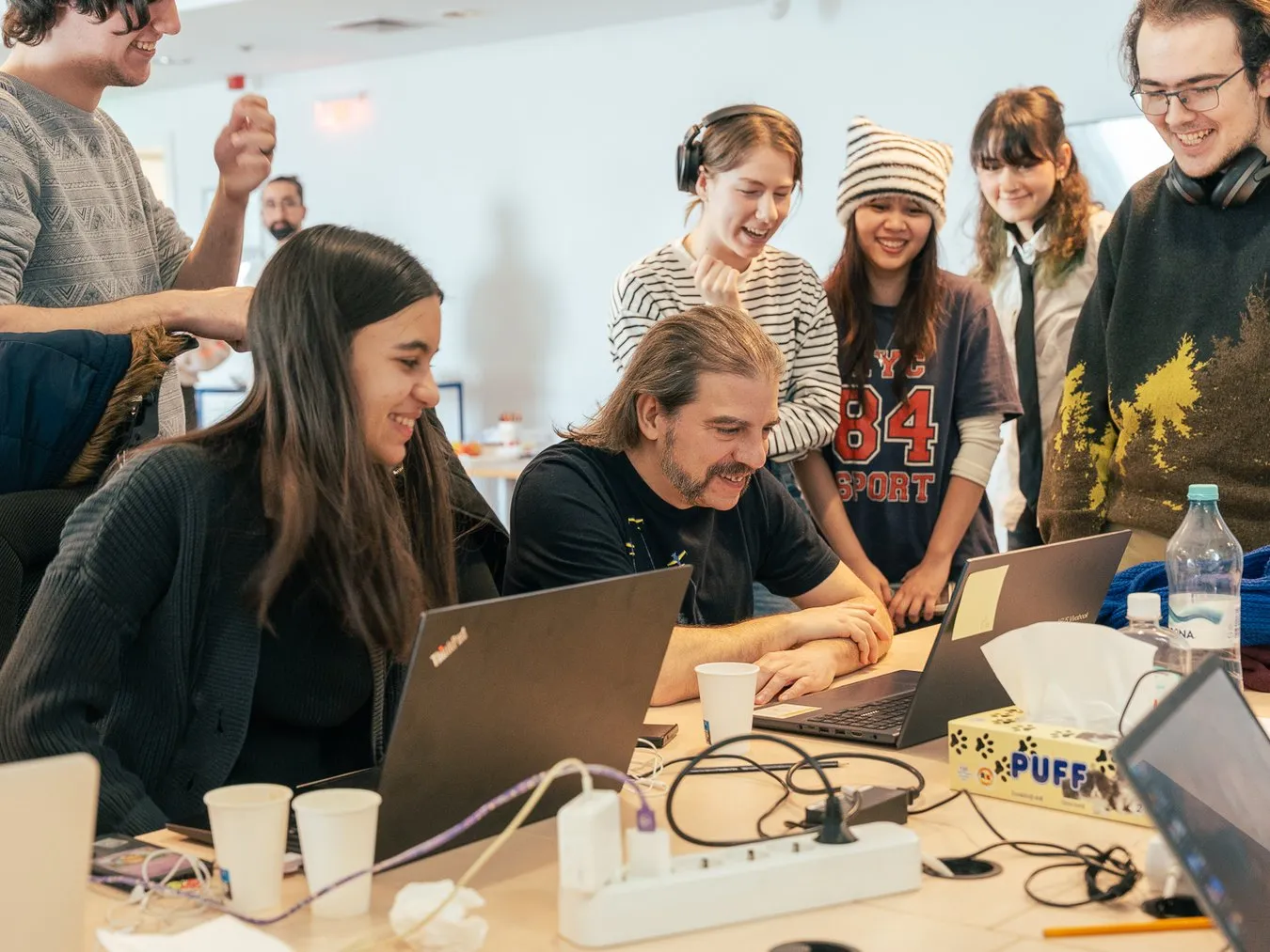 Students gathered around laptops, laughing