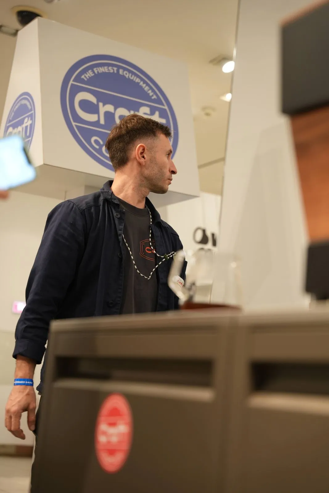 A Craft Coffee team member at the stand, under the round Craft Coffee badge