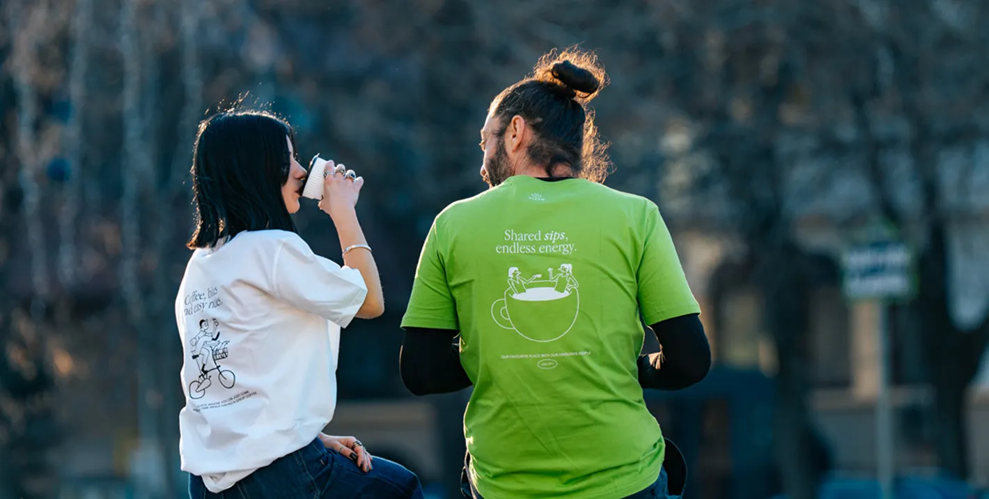 Two people in green Steam T-shirts sitting outside