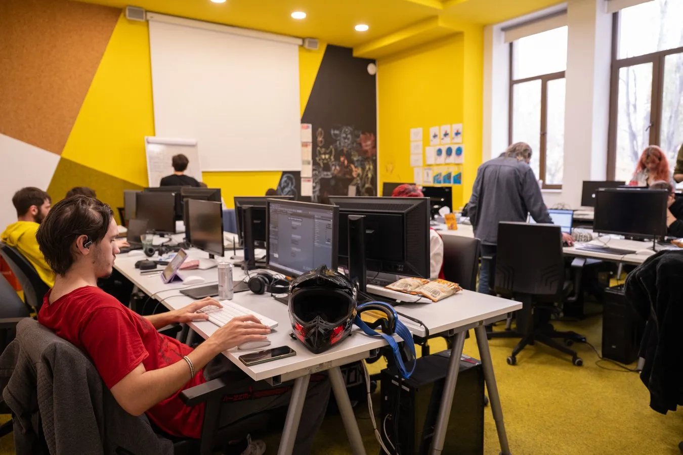 Students at their computers in a bright classroom with yellow walls