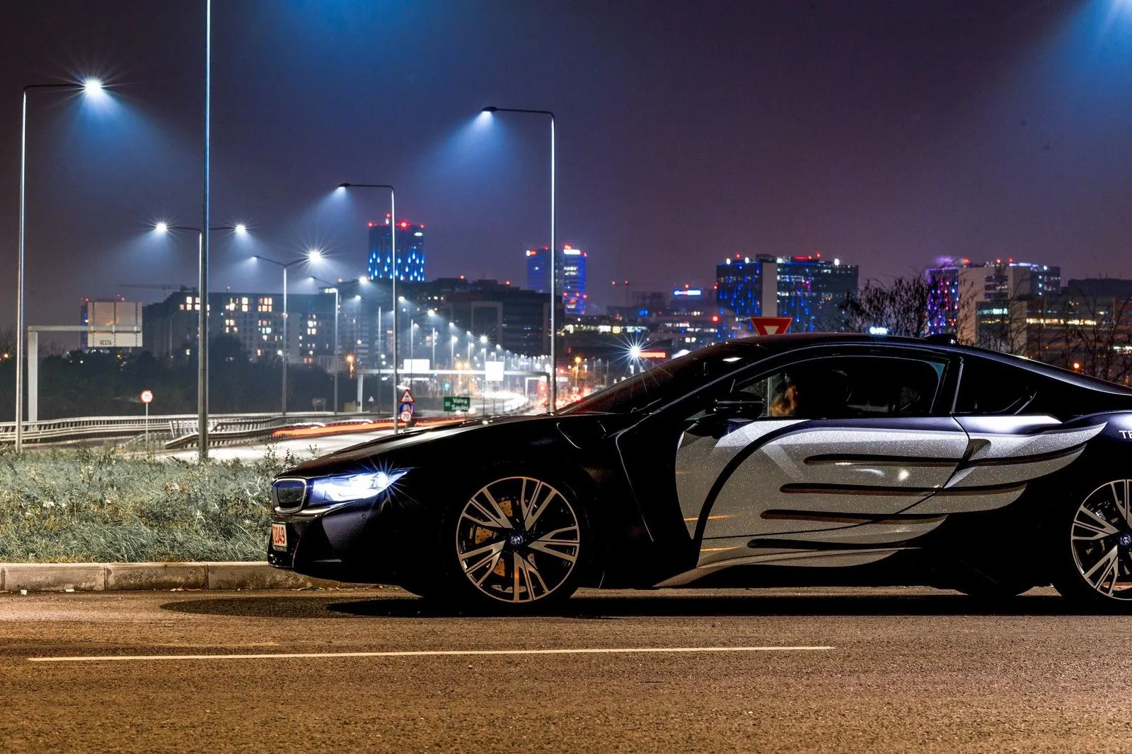 A sports car with silver wings on its side, at night