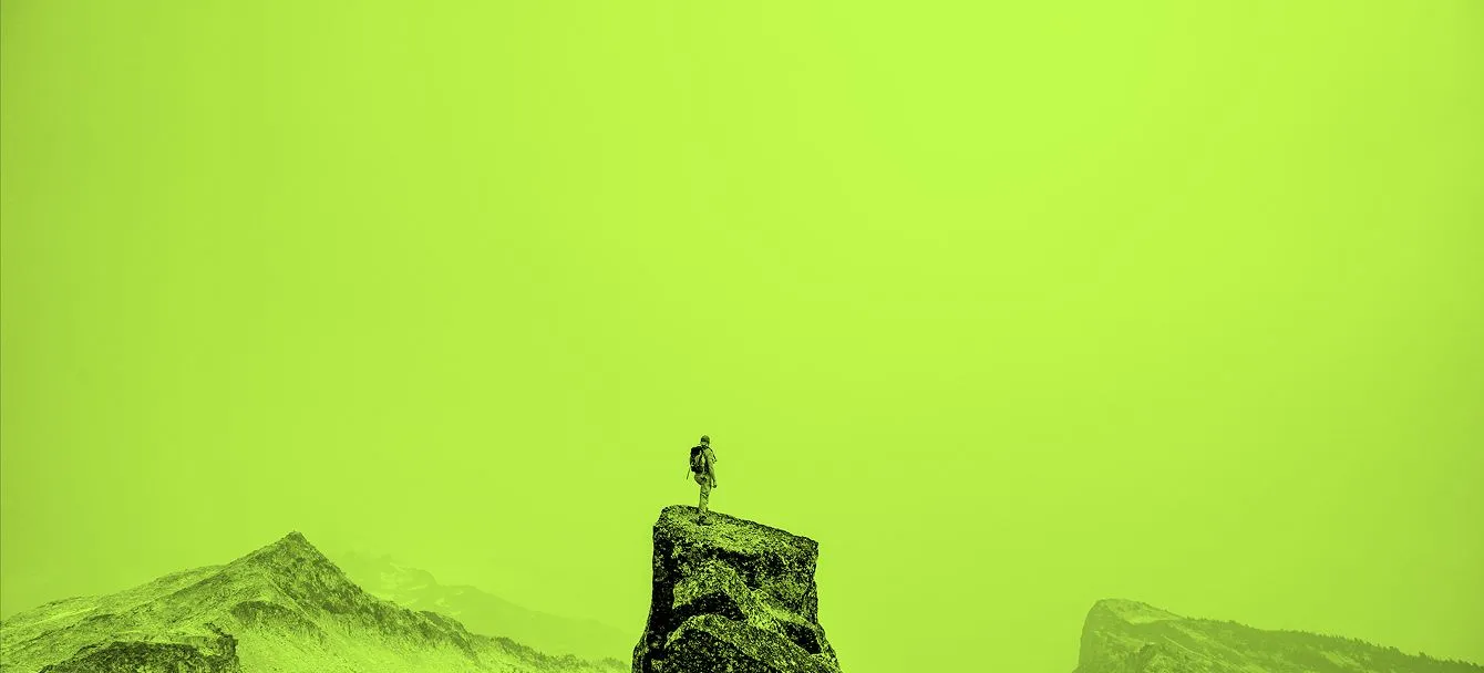 O siluetă pe o stâncă, pe un cer verde lime