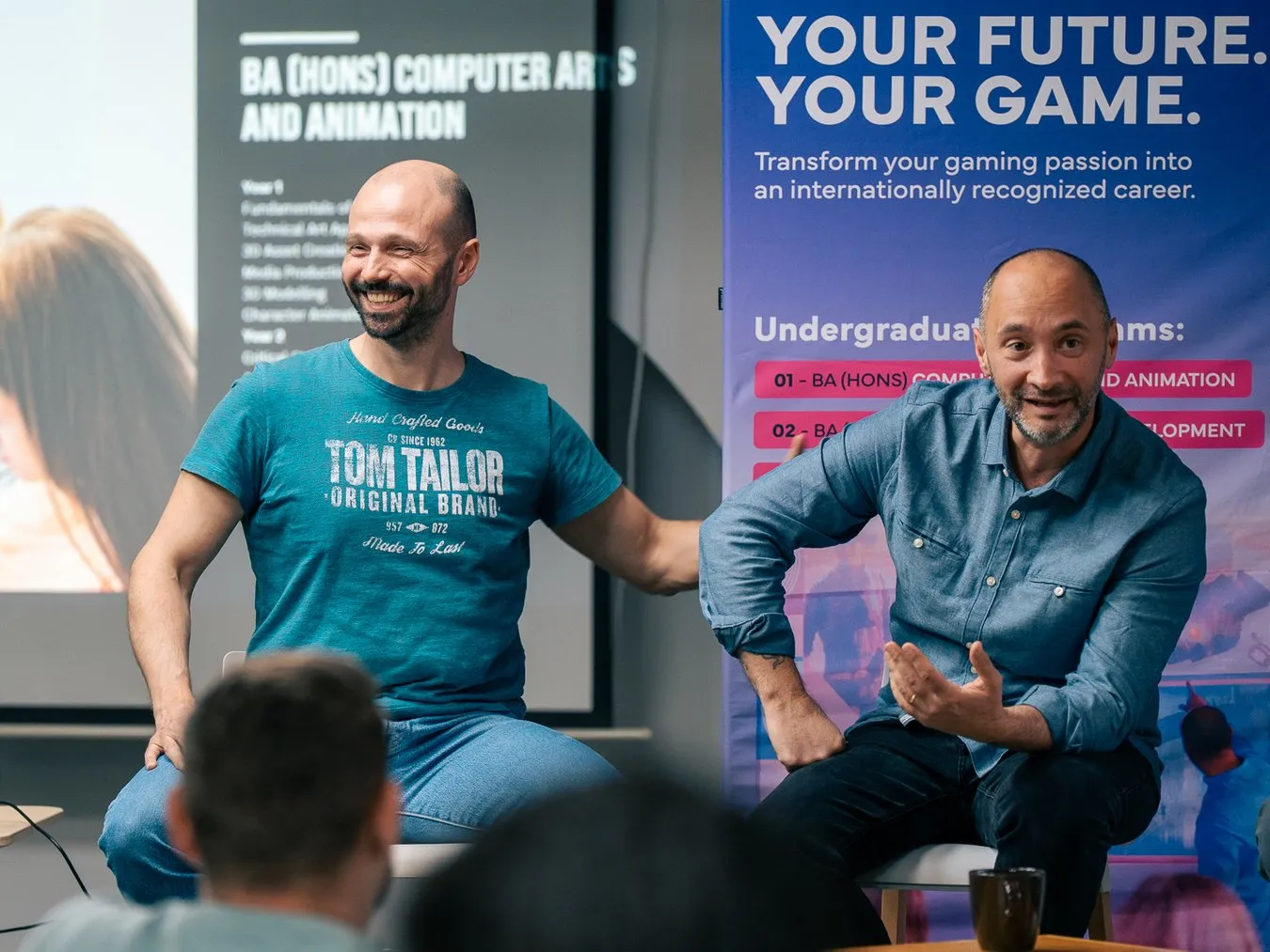 Two speakers on stage in front of a Your future. Your game. banner