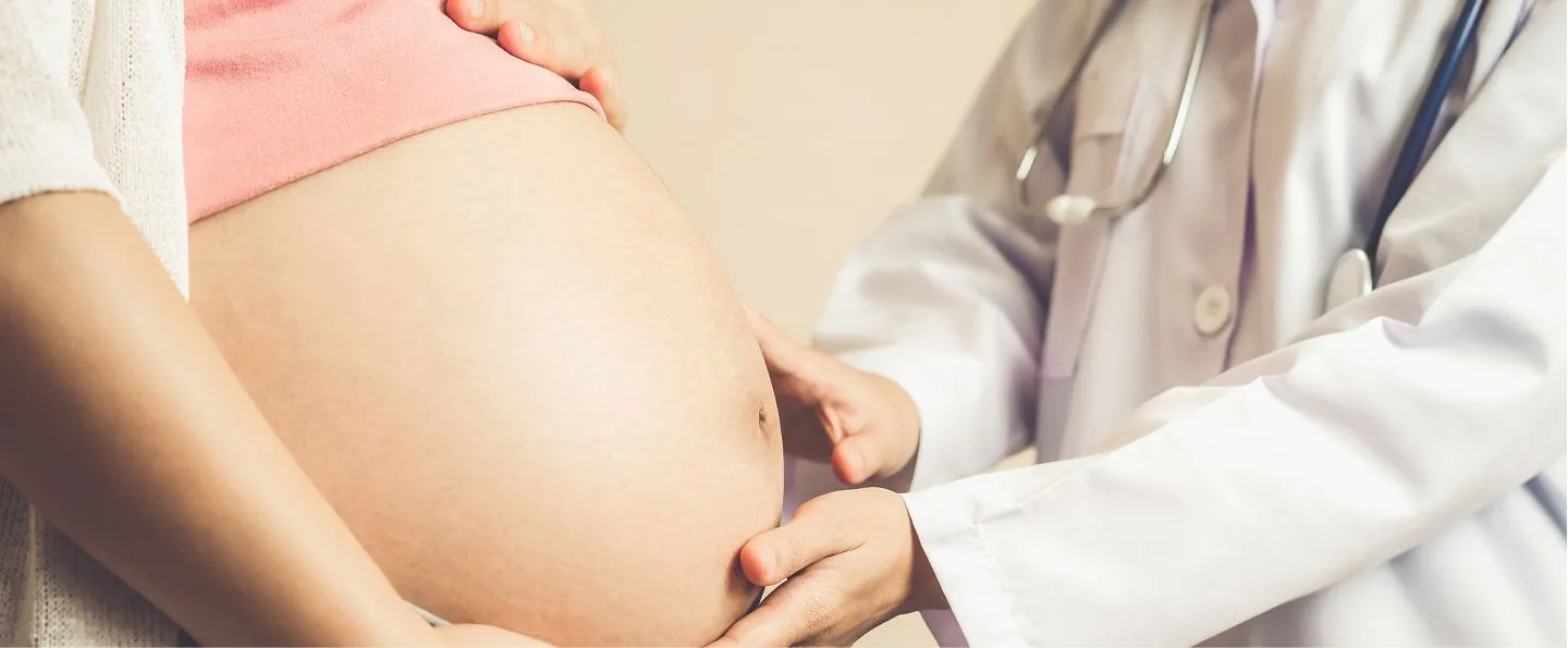 A mother-to-be with a doctor's hands on her belly
