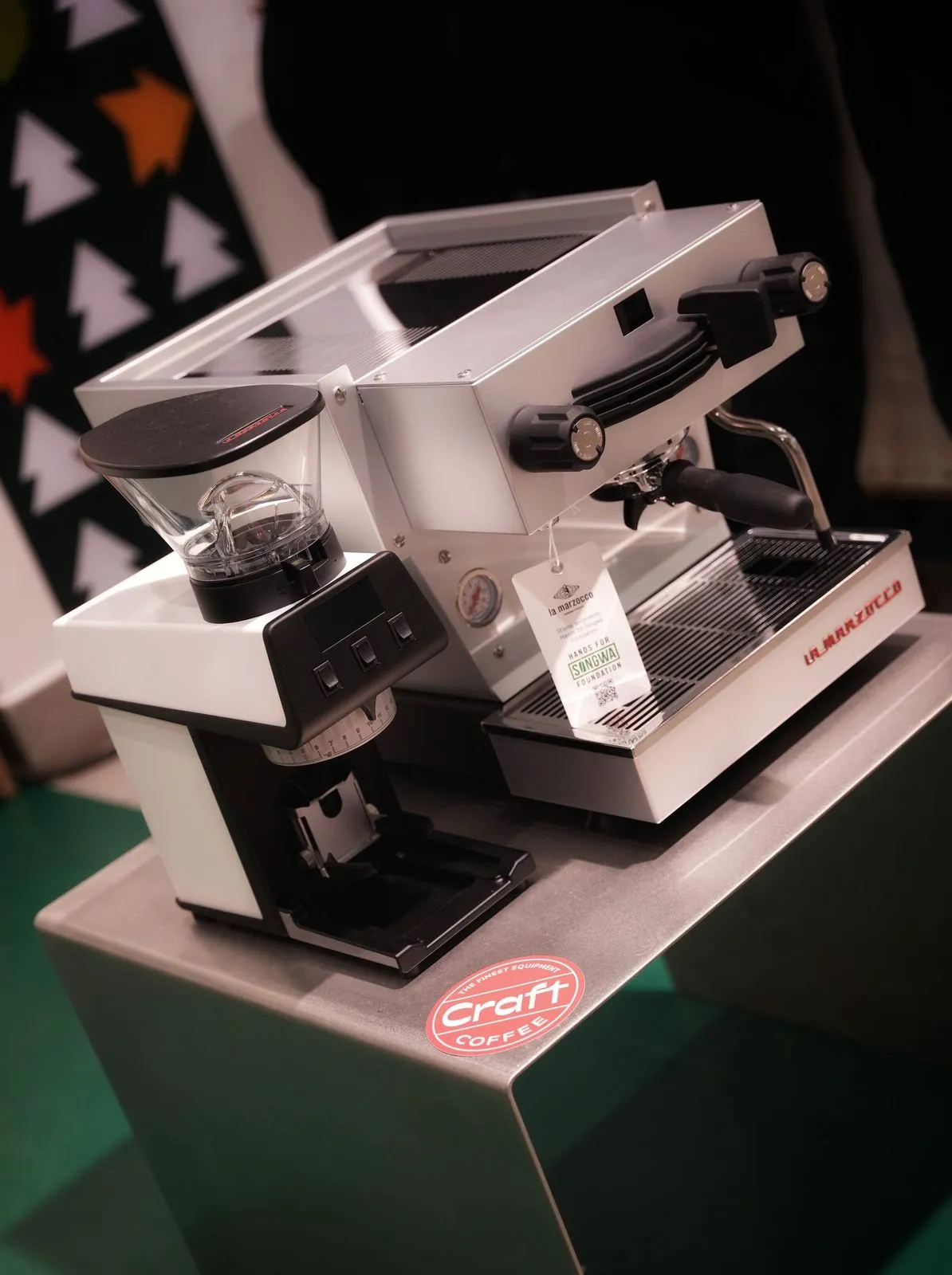A La Marzocco machine and grinder on a dark plinth with the red Craft Coffee badge